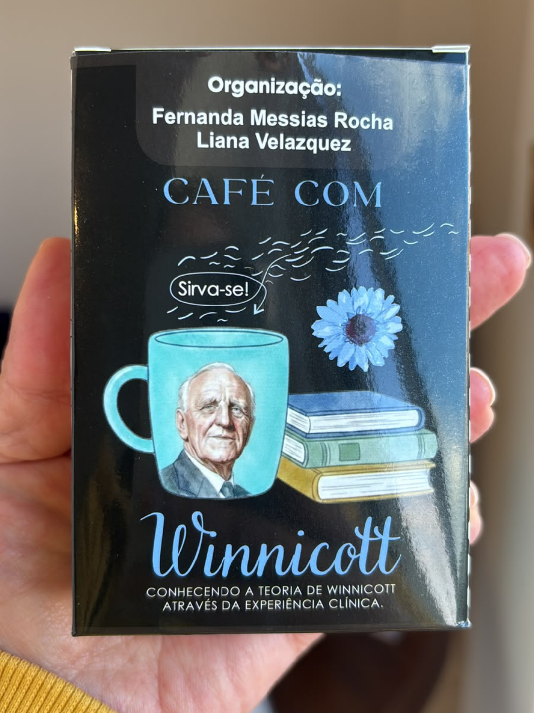 Caixa do livro Café com Winnicott segurada nas mãos